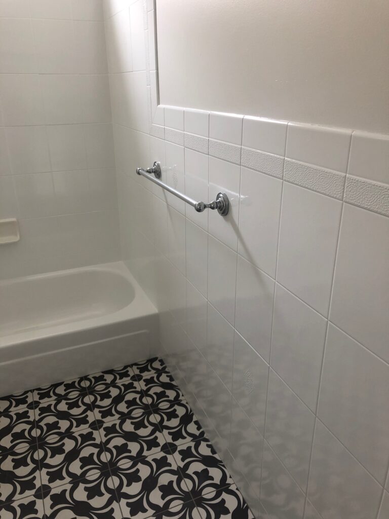 a bathroom with white wall tiles and printed floor tiles